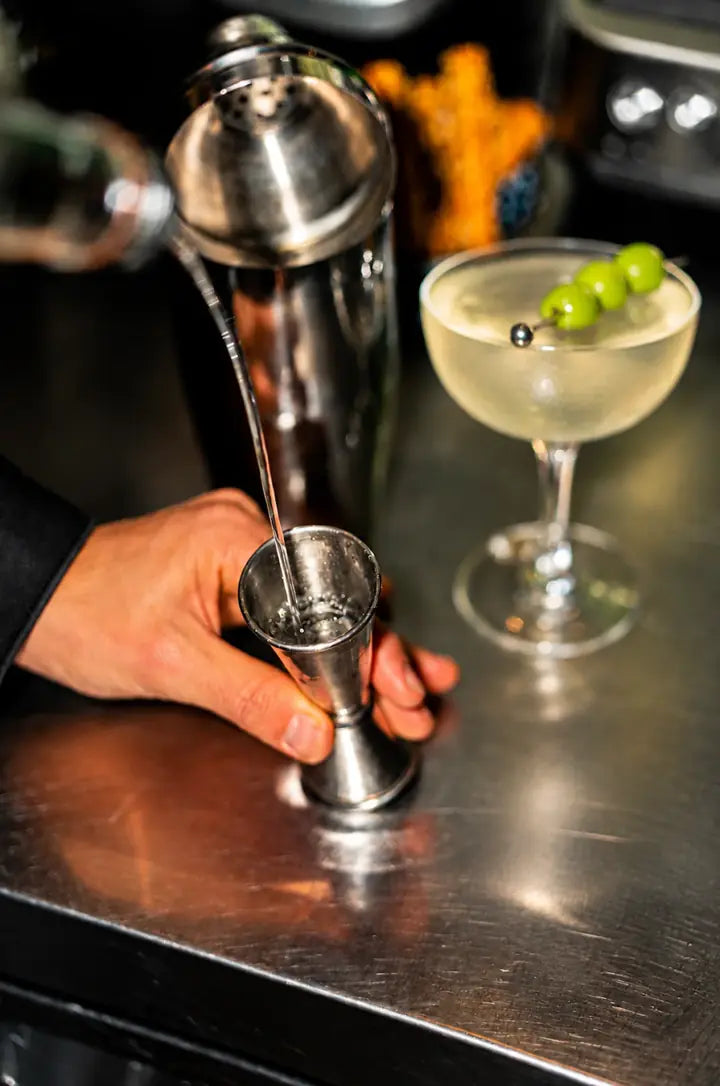 A LeTish bartender presents a cocktail garnished with grapes