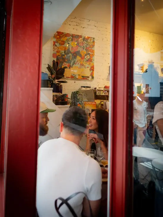 Friends gathered around a table inside LeTish, seen through the red café windows